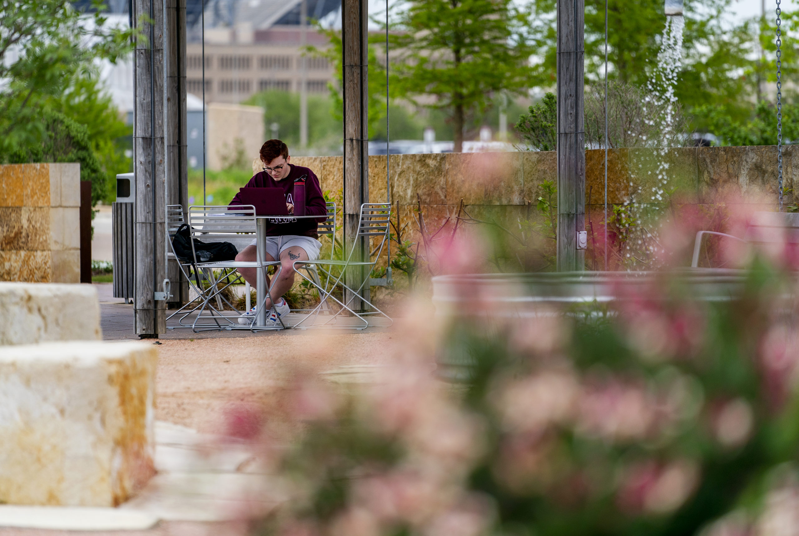 Student sitting at a table outside studying on his laptop