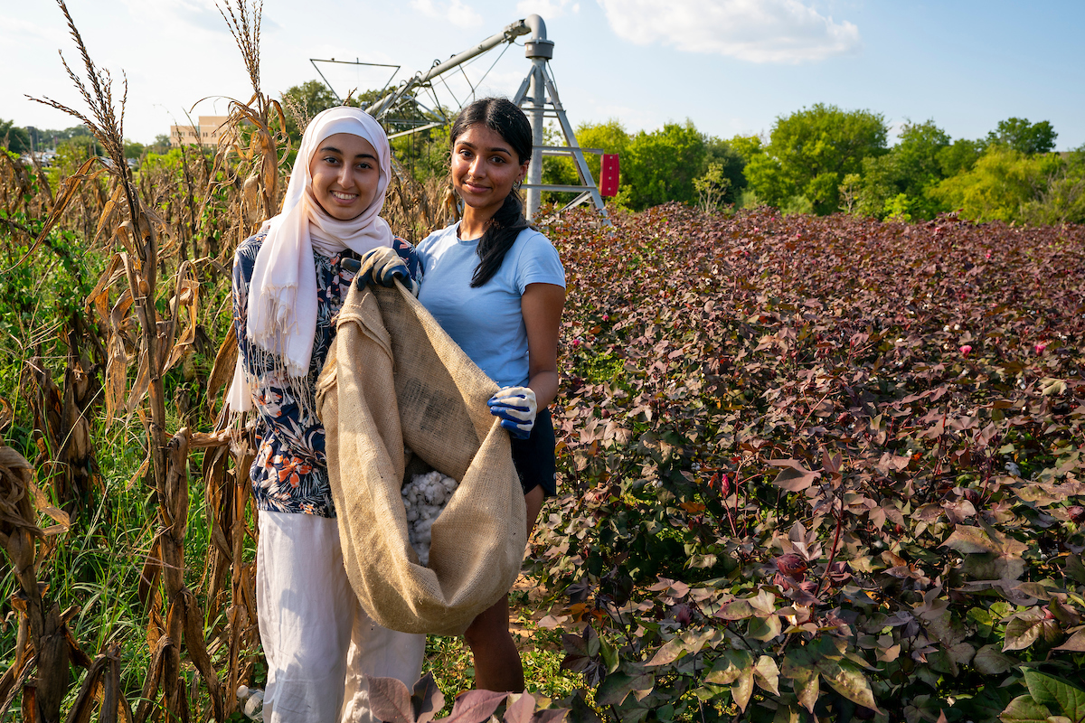 Two girls standing in a field with a sack