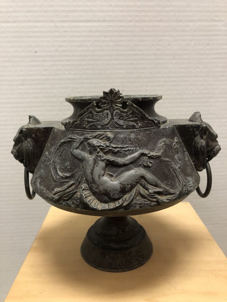 Vase engraved with someone lying down from a view behind the person.